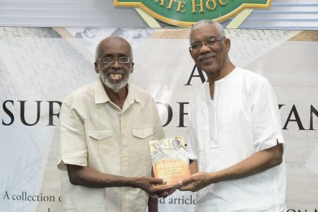 Professor Winston McGowan (left) and President David Granger with a copy of the book. (Ministry of the Presidency photo)