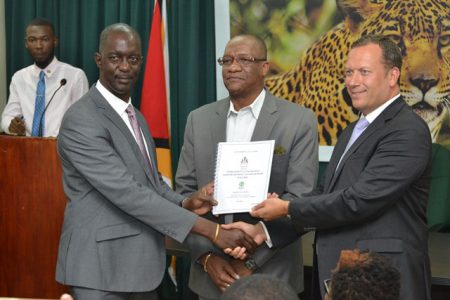 Trevor Benn (left) of GLSC receives the signed contract from Peter Headland of OSI while Minister of State, Joseph Harmon looks on. (Department of Public Information photo)