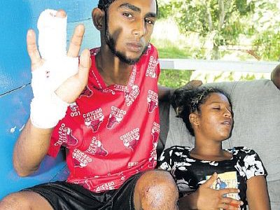Kailash Seepersad shows the injuries he sustained during an altercation outside a Debe nightclub, yesterday. At right is Shantal Roysam, common-law wife of Dillon Lucas who was killed during the fight. (Trinidad Guardian photo)
