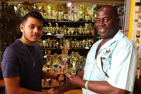  Above, Eshwar Bharrat, a representative of Trophy Stall of Bourda Market, hands over the trophies to former national volleyball player Levi Nedd.