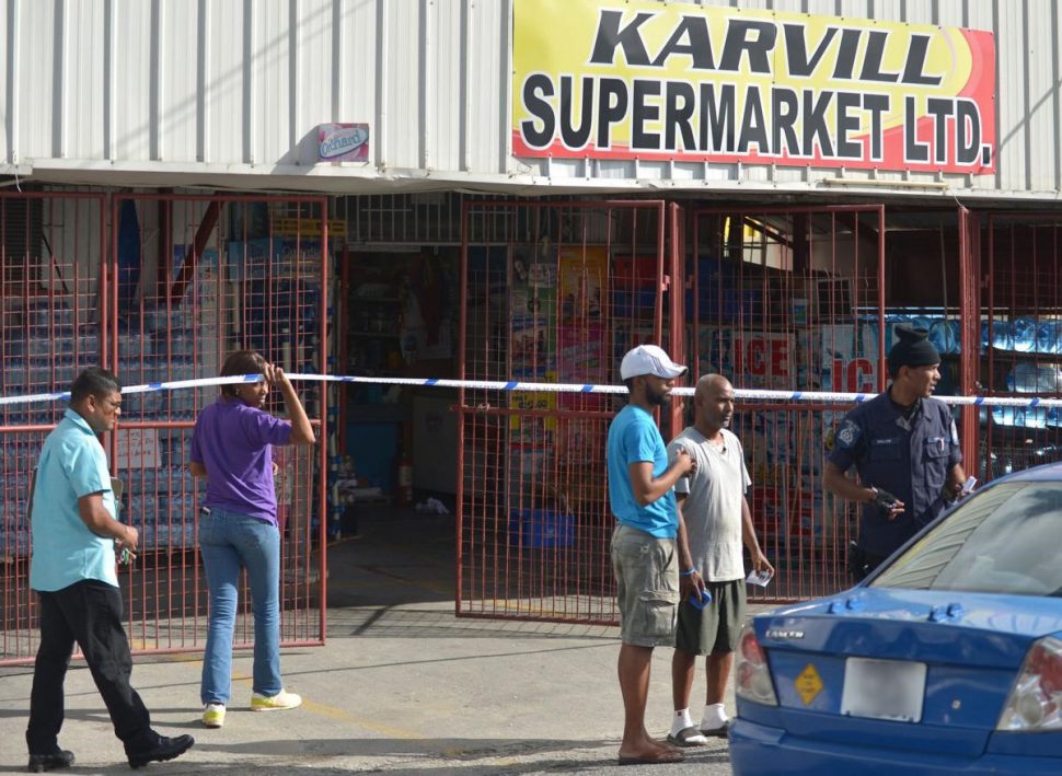 Police officers at the crime scene on Manahambre Road, Princes Town, where a Chinese businessman was killed at Karvill Supermarket yesterday afternoon.