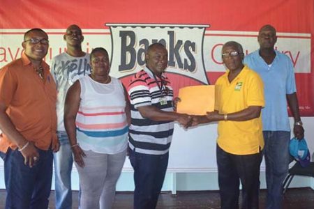Troy Peters, Communications Manager of Banks DIH Limited hands over the sponsorship package to Gladstone George, Vice President of the GNDF in the presence of Transport Sports Club Manager Charles Greaves and team representatives.
