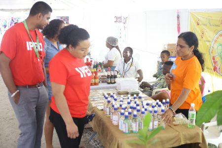  Patrons examining what Natural Choice products had to offer on Saturday at the agro-processing festival, Uncapped at the National Track and Field Centre, Leonora. They had on exhibition nine scented extra virgin coconut oils, Chai and Moringa tea and a mixture of both.  (Terrence Thompson photo)
