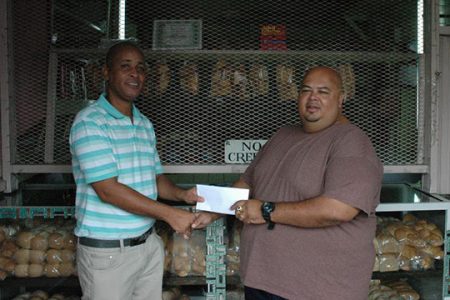 Yhip’s Bakery representative Troy Yhip (right) hands over the cheque to Three Peat Promotions Rawle Welch on Monday.