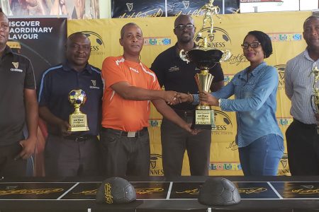Tournament coordinator and principal of Three Peat Promotions Rawle Welch (3rd from left), collecting the championship trophy from Colours Boutique representative Samantha Thomas in the presence of (left to right)Referees Coordinator Wayne Griffith, Banks DIH Communications Director Troy Peters, Guinness Brand Manager Lee Baptiste, and Banks DIH Outdoor Events Manager Mortimer Stewart
