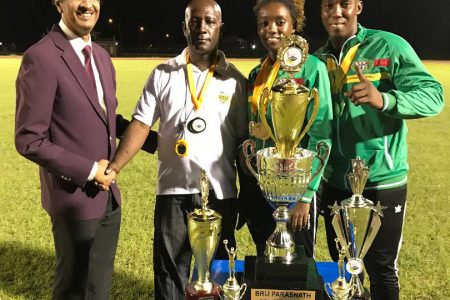 Brij Parsnath congratulates University of Guyana Team coach Mark Scott while  champion female athlete Ruth Sanmoogan, second right and champion male athlete Osafa Dos Santos  look on.
