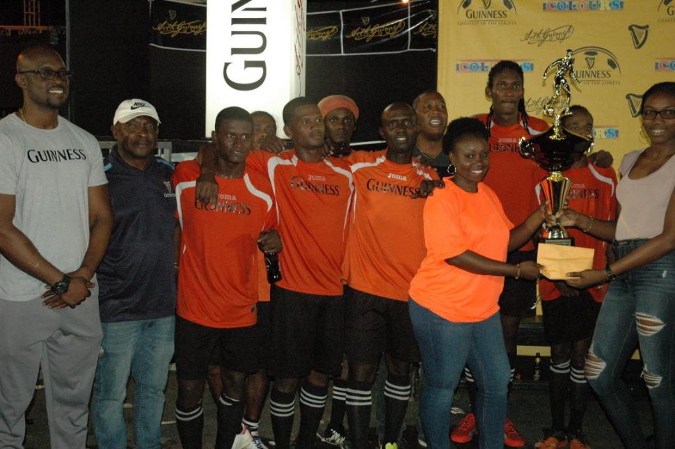 Colours Boutique Creanna Damon hands over the first prize and trophy to Gold is Money representative in the presence of teammates and Guinness Brand Manager Lee Baptiste (left). Also in the photo is Banks DIH Communications Manager Troy Peters (2nd from left) and Outdoor Events Manager Mortimer Stewart (5th from right)