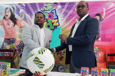 Samuel Arjune, Guyana Beverage’s Incorporated Commercial Manager (left) and GFF president Wayne Forde, displaying the signed MOU for the ‘Fruta Kool Kidz’ National Grassroots Programme.