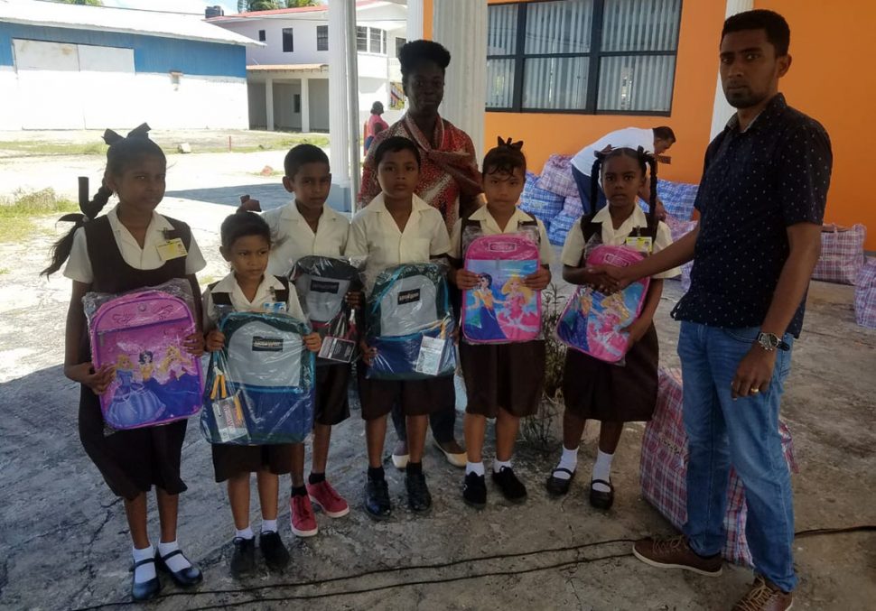 A representative from the Region Three Private Sector Association handing over backpacks to students. (DPI photo)
