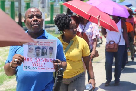 Chair of the South Georgetown Branch of the Guyana Teachers’ Union (GTU) Kirwyn Mars carries a placard stating that the “CAPE and CSEC top students back the teachers’ strike and so should you” at yesterday’s protest action in front of the Ministry of the Presidency. The placard includes a headline from the Sunday Stabroek of August 19. 