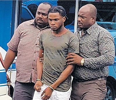 Kareem Phillip is escorted to the Scarborough Magistrates Court in Tobago, charged with the murder of 15- year-old national footballer Abiela Adams