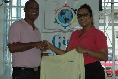Public Relations Officer Sophia Dolphin (right) hands over one of the jerseys to Three Peat’s Rawle Welch on Monday.