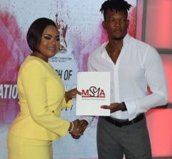 Min­is­ter of Sport and Youth Af­fairs, Sham­fa Cud­joe presenting Keshorn Walcott with a copy of the Na­tion­al Pol­i­cy on Sport 2017 – 2027 