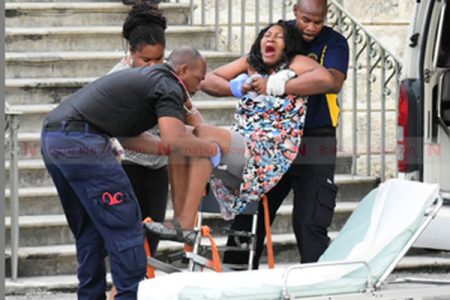 Guyanese accused Hannah Reid cries out in pain as she is lifted onto a stretcher and into a waiting ambulance for transportation to the Queen Elizabeth Hospital. (Picture by Heather-Lynn Evanson.)
