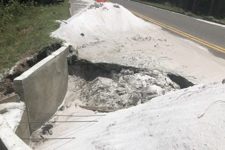 The large hole on the Long Creek Public Road surrounded by two piles of sand, which covered the entire lane. 