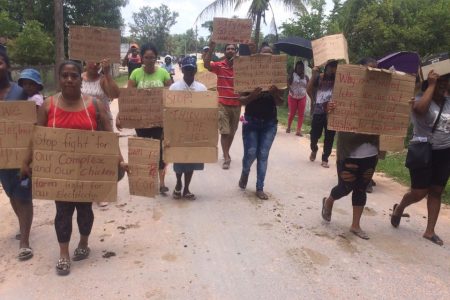 Residents of Kwakwani march through the community with their placards during the protest yesterday morning.