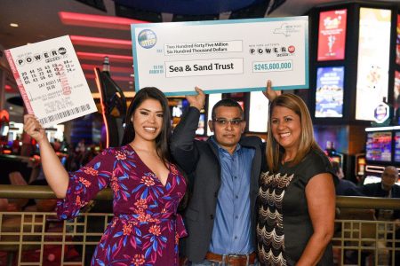 Nandlall Mangal (at centre) holds up check for $245,600,000 after winning New York Lottery’s Powerball Game. He was joined by New York Lottery MC Amanda Serrano (left) and New York Lottery’s Yolanda Vega at Resorts World Casino in Queens on Thursday. (Photo by David Wexler for New York Daily News)