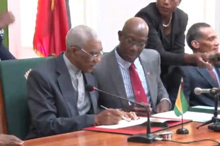 President David Granger (left) and Prime Minister Keith Rowley signing the MOU
