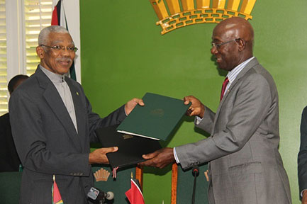 President David Granger (left) and Trinidadian Prime Minister Dr Keith Rowley exchanging copies of the MoU yesterday at State House.