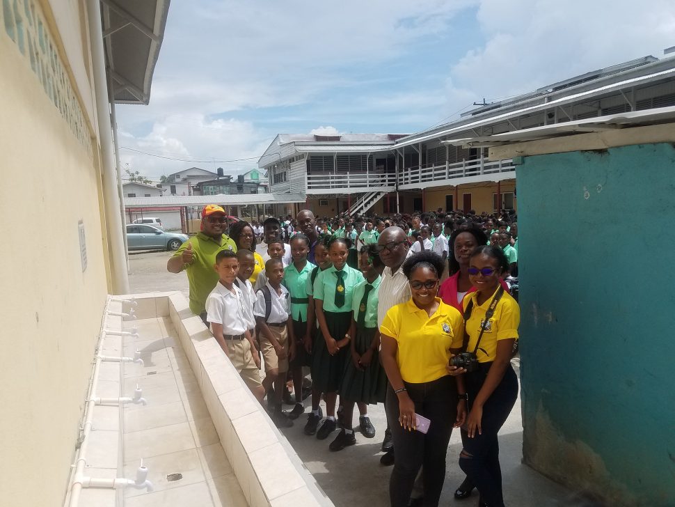 Members of Nulli Secundus, students of the Charlestown Secondary School and Chief Education Officer Marcel Hutson (fourth from right), pose for photographs at the newly built wash bay.
