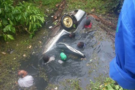 Rescuers trying to save the victims on Monday following an accident at Zealand Public Road, Mahaicony 