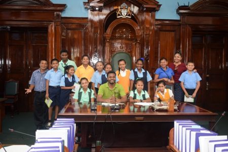 Students and teachers of the Hinterland Regions with Public Relations Officer, Yannick December and Shavon Joseph, staff of Ministry of Indigenous People’s Affairs in the National Assembly room. (DPI photo)