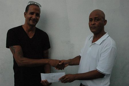 Rawle Welch (right) of Three Peat Promotions, coordinators of the Guinness Cage Street-ball Championship, collecting the sponsorship cheque from Courtney Benn Contracting Services representative Johan Feedee