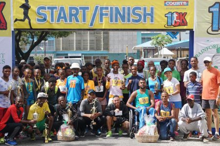 The prize winners of the eighth edition of the Courts 10k pose for photo following the event yesterday outside the company’s headquarters on Main Street. (Orlando Charles photo)