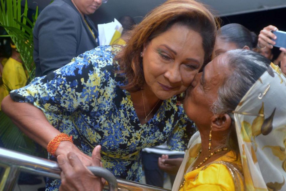 Opposition Leader Kamla Persad-Bissessar is kissed by a supporter during the UNC Monday night meeting at the Union Presbyterian Primary School on Monday night. 