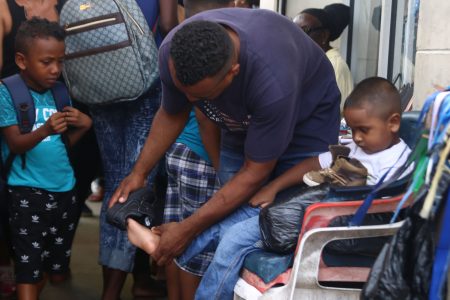 A parent fits his child with a boot on Regent Street yesterday. (Terrence Thompson photo) 