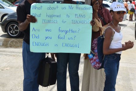 Striking teachers with a message for President David Granger on Brickdam yesterday. (Orlando Charles photo)
