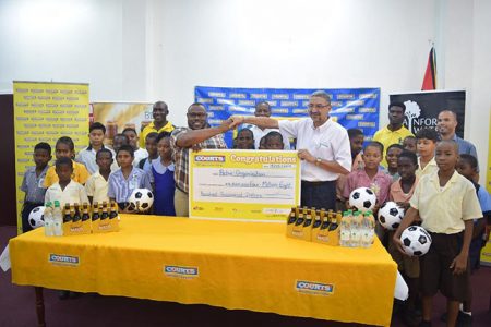 Petra Organization Co-Director Troy Mendonca collecting the sponsorship cheque from Courts Guyana Inc. Managing Director Clyde DeHaas in the presence of students from several of the participating teams.