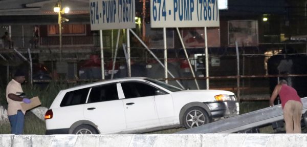 A police officer, left, oversees the wrecking of the vehicle in which kidnap victim Natalie Pollonais was being transported along the Churchill Roosevelt Highway in El Soccorro, San Juan, last night.