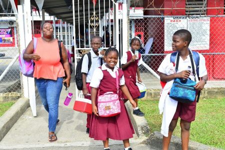 This parent collects her children early on Friday due to a reduced staff turnout at the Montrose Government Primary School, Chaguanas, yesterday. 