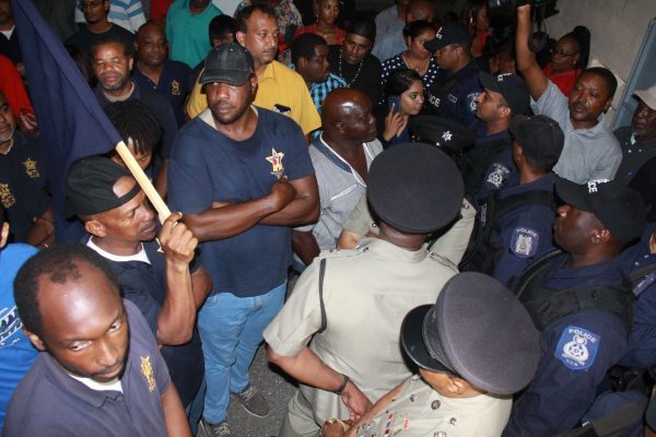 Police officers block OWTU members from entering the PNM’s public meeting at the Marabella Community Centre last night.