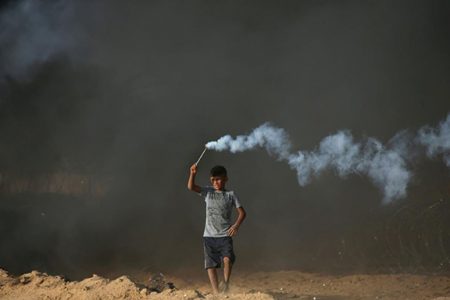 A Palestinian boy holds a tear gas canister fired by Israeli troops during a protest calling for lifting the Israeli blockade on Gaza and demanding the right to return to their homeland, at the Israel-Gaza border fence in the southern Gaza Strip October 5, 2018. REUTERS/Ibraheem Abu Mustafa
