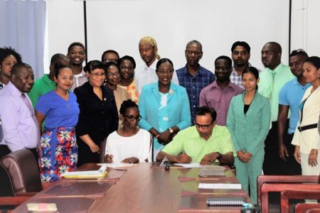 Two of the Master Trainers signing their contracts in the presence of colleagues, Minister of Education Nicolette Henry (at centre), Permanent Secretary Adele Clarke (seventh, from left) and GSEIP Project Coordinator Jimmy Bhojdat (third, from left). (Ministry of Education photo)