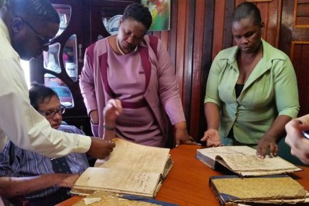 Chairman of the CoI into the operations of the City administration retired Justice Cecil Kennard (second from left) along with legal assistant Sherwin Benjamin (left) examining the “missing record books” at City Hall while assistant Town Clerk Sherry Jerrick (right) looks on.