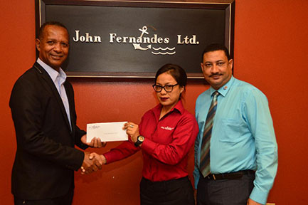  AAG president Aubrey Hutson receives a cheque for an undisclosed sum from John Fernandes Limited’s Accounts Executive Tricia Azaire. Also in photo, is executive Peter Peroune.