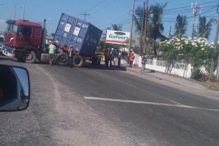 This container truck caused a disruption to the rush hour traffic along the East Bank corridor at First Street, Mc Doom in the vicinity of the Shell Service Station yesterday afternoon, when its driver reportedly attempted to make a right turn. In the process of turning, the container became detached from its bed and was left in a tilted position. Despite the truck taking up two lanes and partially blocking trafficking on the other side of the road, drivers travelling in both directions could be seen jostling each other to get past the truck. Stabroek News was informed that the truck was safely remove sometime later (Zoisa Fraser photo)