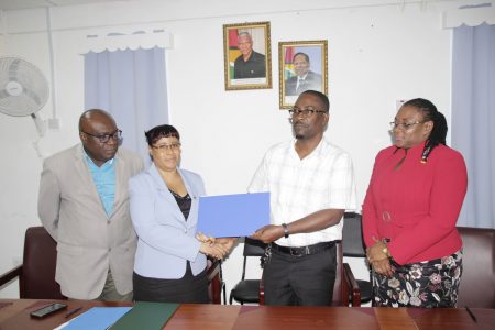 Ministry of Education Permanent Secretary shakes hands with GTU President Mark Lyte after the signing of the agreement on salary and non-salary benefits for teachers as Chief Education Officer Marcel Hutson and GTU General Secretary Coretta McDonald look on. 
