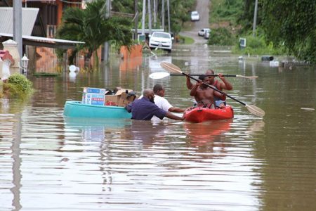 Iman Alimool Rahim, left, with assistance from the Mafeking Masjid, distributing food items during the flooding. (Trinidad Guardian photo)