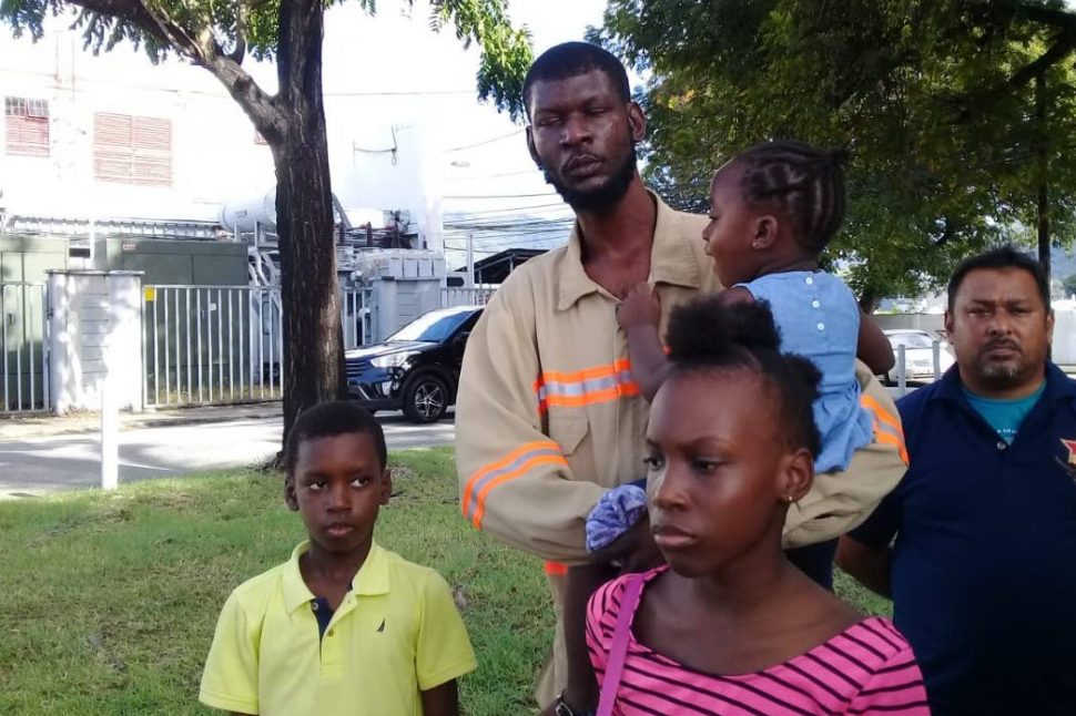 Kevin Julien with his three children yesterday at TTEC’s Flament Street, Port of Spain station yesterday.
