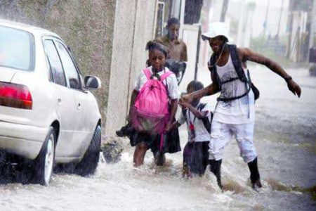 A man assists children on flooded Maxfield Avenue. 