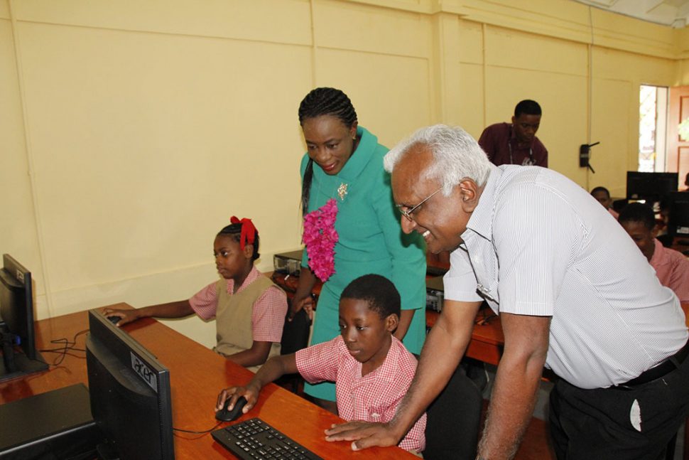 Minister of Education, Dr Nicolette Henry (standing at left) and Head of the Management Information Systems Unit within the Ministry of Education, Yoganand Indarsingh (standing at right) engaging students of Eccles Primary School in their IT Lab. (Ministry of Education photo)
