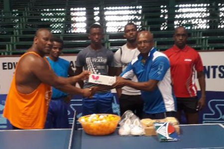 Patrick `PJ’ Jones, left, hands over the table tennis equipment to secretary of the Guyana Table Tennis Association, Linden Johnson recently at the Cliff Anderson Sports Hall in the presence of national players Joel Alleyne and Nigel Bryan.
