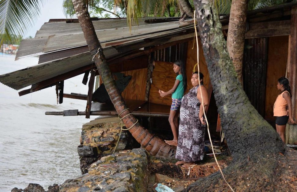 Marabella resident Seema Hosein stands with her children at Bayshore Marabella where the kitchen and bedroom of her parents house were destroyed by large waves following bad weather in the area on Saturday evening. 