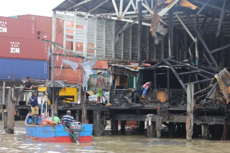 Persons searching the burnt remains of stalls at the Stabroek Market wharf (Photo by Terrence Thompson)