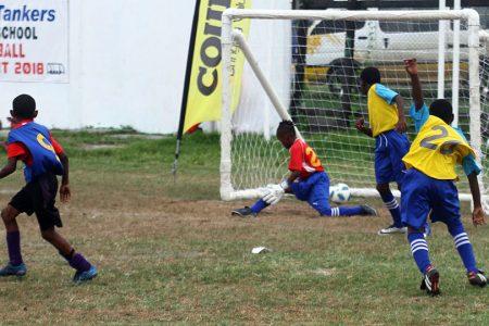 Jamal Fraser [left/no.9] of St. Pius, scoring the winning goal against Tucville during their semi-final clash in the Courts Pee Wee Primary School Football Championship at the Ministry of Education ground
