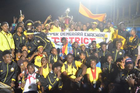 Athletes and officials of Upper Demerara/Kwakwani celebrating last evening at the National Track and Field Centre with the Champions of Champions trophy with Non-Alcoholic Brand Manager from Banks DIH Limited, Clayton McKenzie. (Orlando Charles photo) 